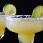 Two virgin margaritas in glasses rimmed with salt and garnished with a lime wheel. Overlay text at top of image.