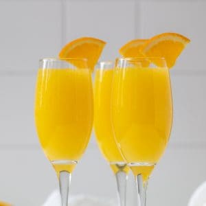 Closeup view of three mimosas garnished with orange slices.