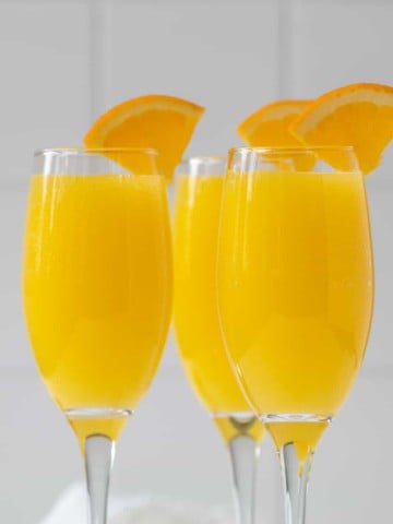 Closeup view of three mimosas garnished with orange slices.