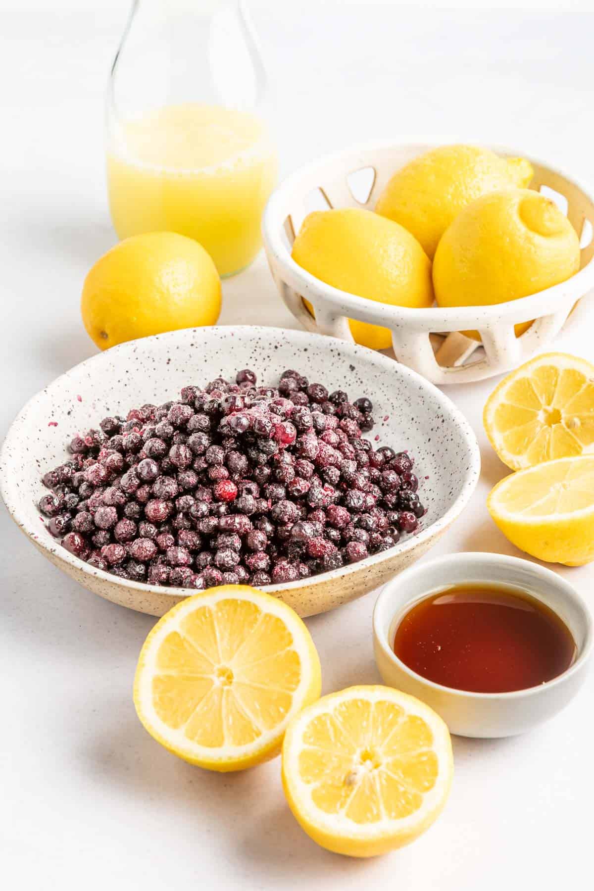 Blueberries in a bowl, maple syrup in a bowl, lemons and lemon juice.
