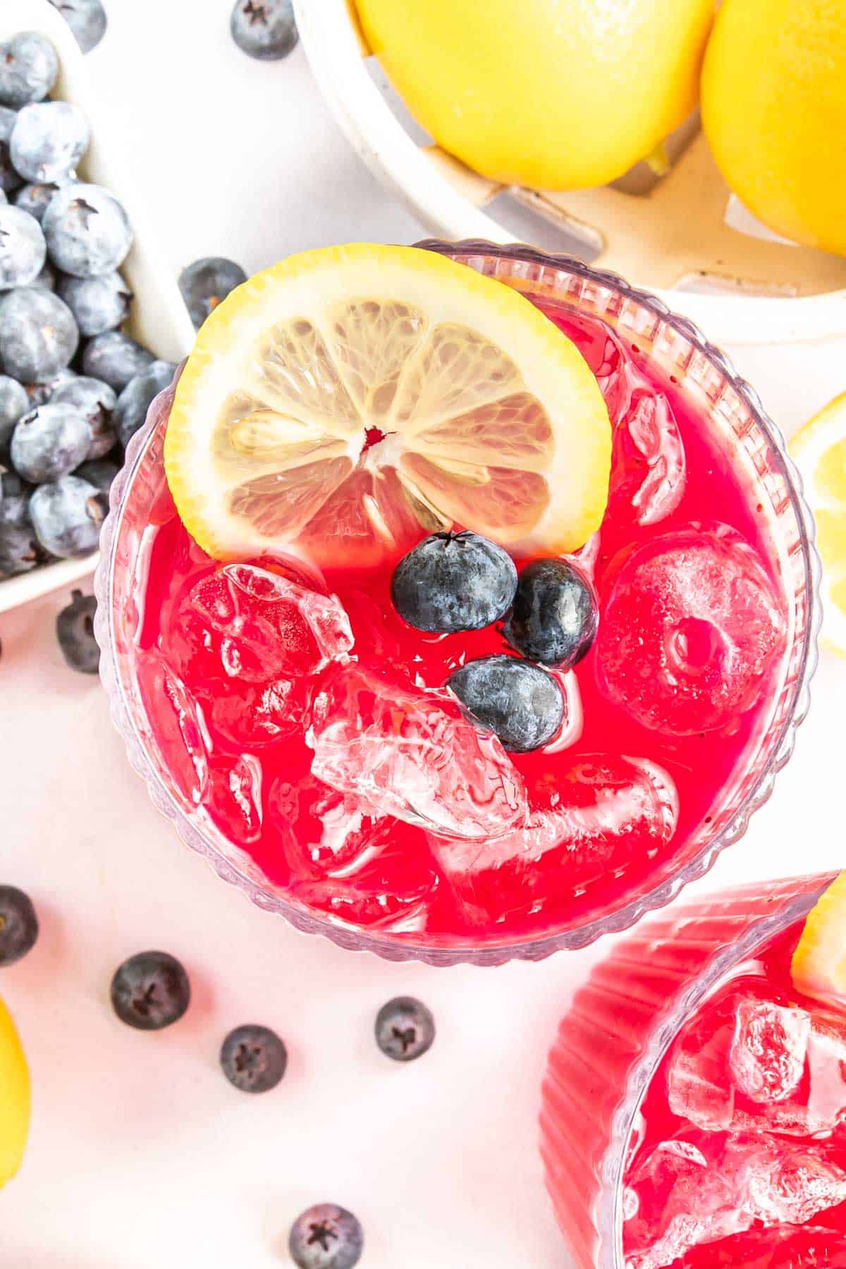 Overhead view of a glass of blueberry lemonade garnished with blueberries and a lemon slice.