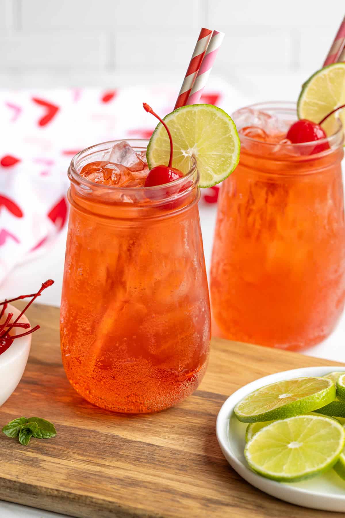 A garnished Shirley Temple mocktail with two paper straws.