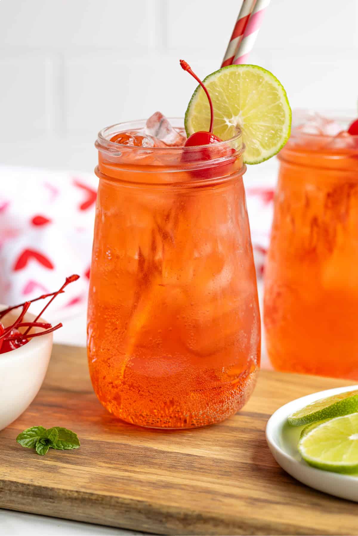 A garnished Shirley Temple mocktail drink with two paper straws.