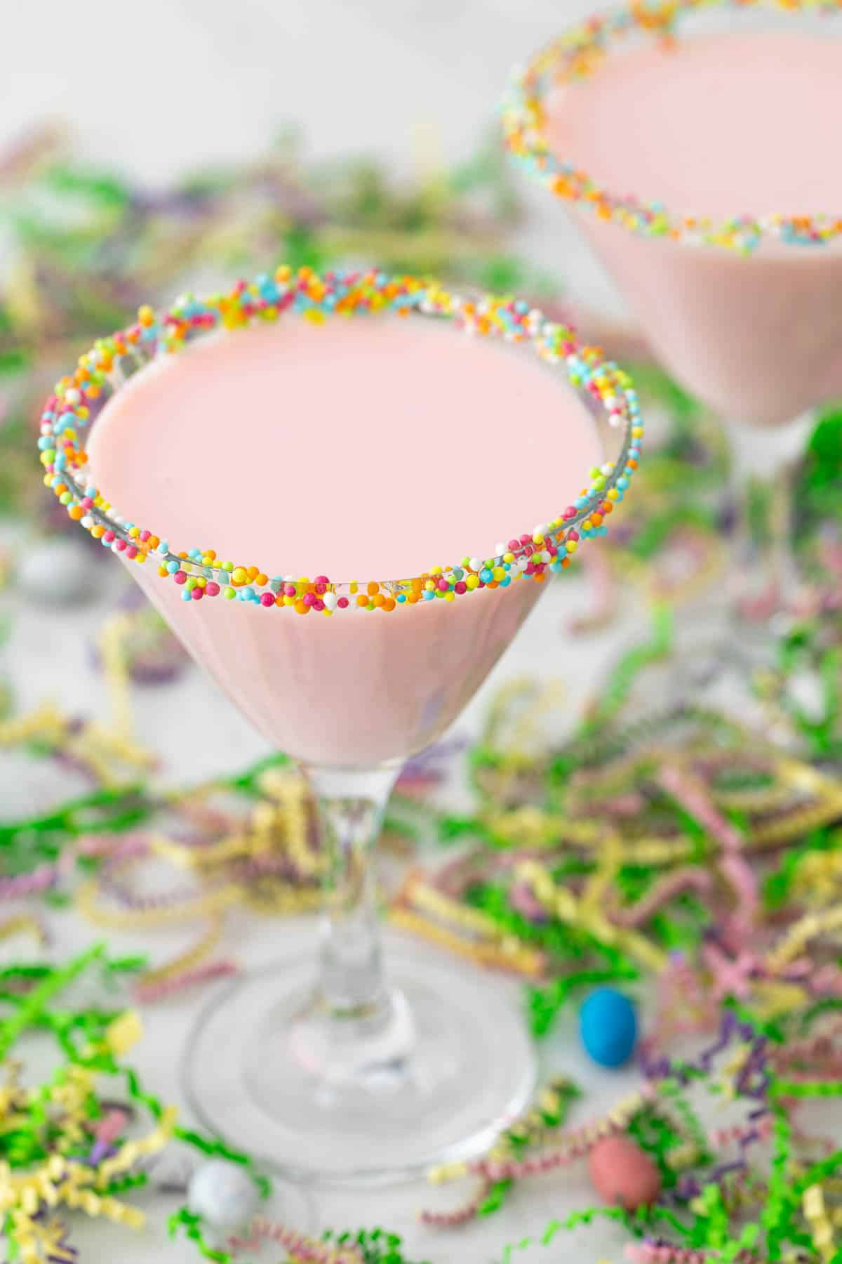 Angled view of a pink mocktail in a glass rimmed with Easter sprinkles.